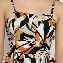 Zoomed-in front view of a tropical leaf print strappy mini dress in shades of black, orange, and beige, showing the neckline and fitted bodice detail.
