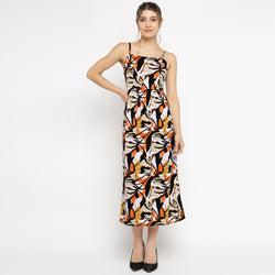 Front view of a woman posing in an abstract floral print midi dress with spaghetti straps, styled with black heels, against a plain white background.