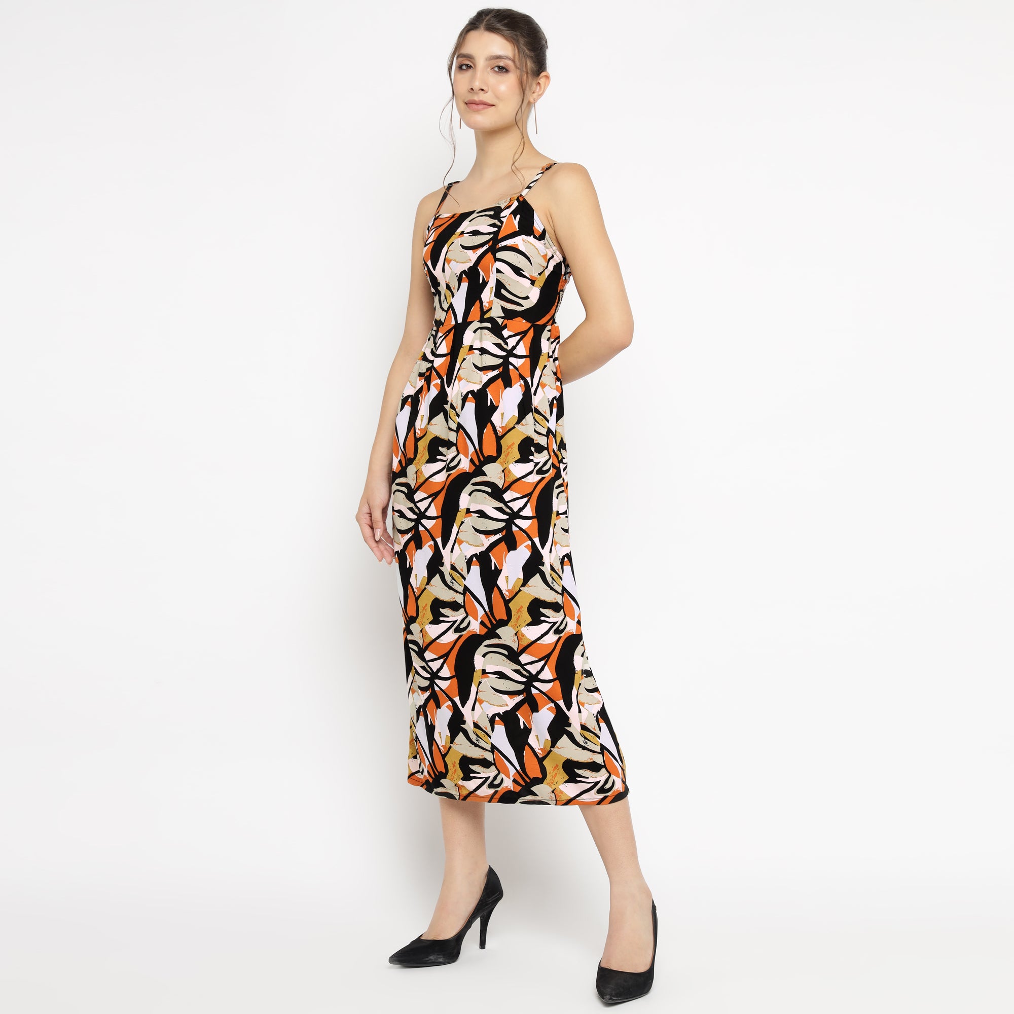 Woman wearing an abstract floral print midi dress with spaghetti straps and black heels, posing against a white background.