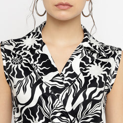 Close-up front view of a sleeveless collared top from a black and white abstract printed co-ord set, showcasing the bold mixed patterns and textured fabric. The model is wearing large hoop earrings, with only the lower half of her face visible against a plain white background.









