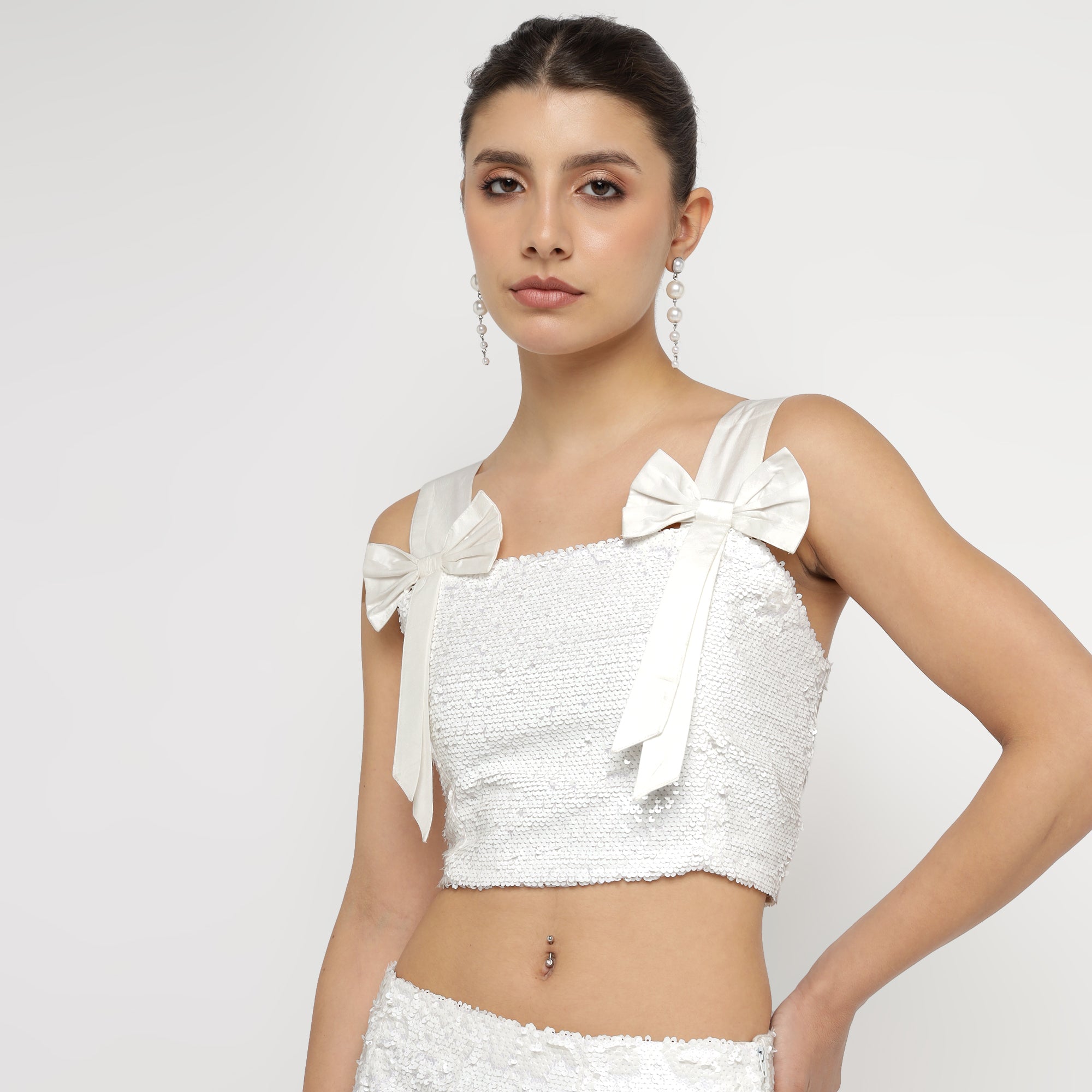 Model wearing a stylish White Embellished Sequin Co-ord Set featuring a sleeveless bow-tie strap crop top, showcased on The Ulluu online store product page